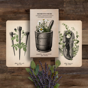 The Folk Magic expansion pack and two cards (coffin nails and hagstone) against a wooden background with lavender flowers below